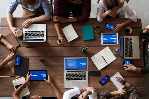 pexels-photo-3183150-3183150-1 Overhead view of a diverse team in a business meeting using laptops and tablets.